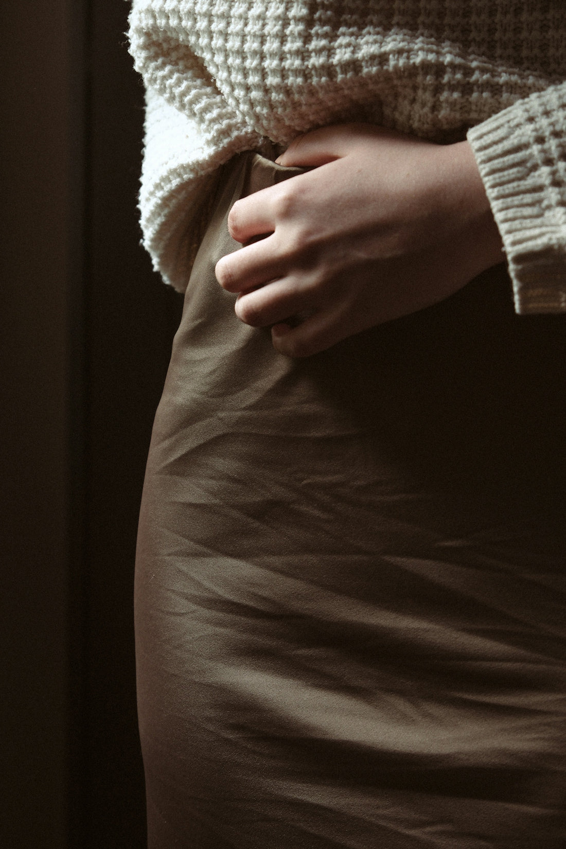 a woman in a skirt with her hands on her stomach