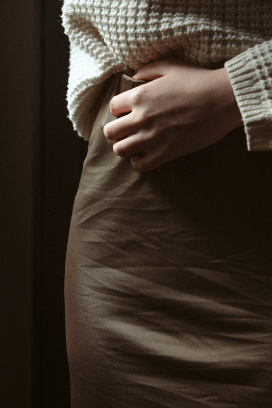 a woman in a skirt with her hands on her stomach