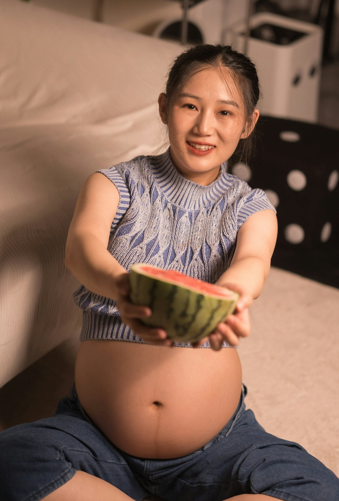 A pregnant woman sitting on the floor holding a bowl