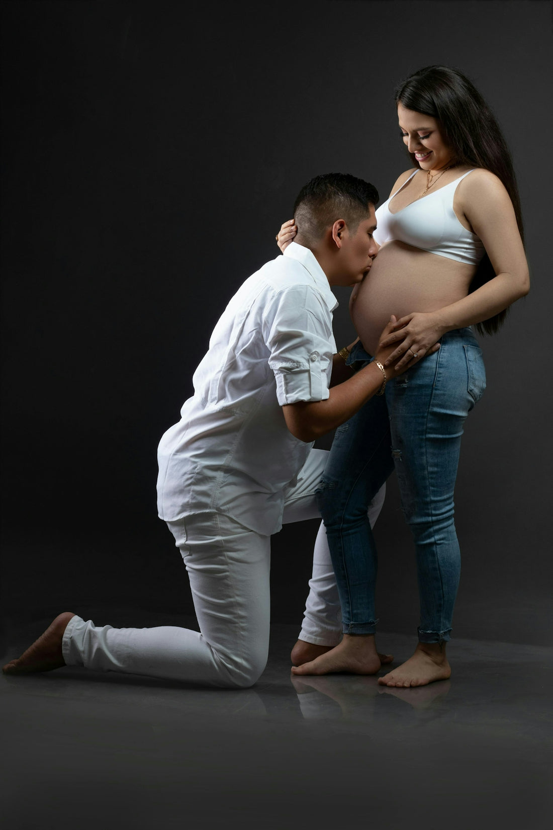 A couple is lovingly posing for a maternity photoshoot.