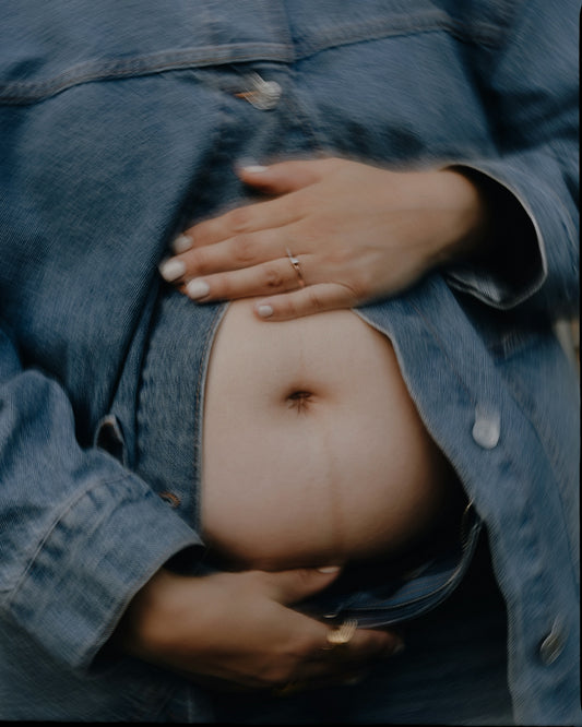 Pregnant belly with hands cradling it.